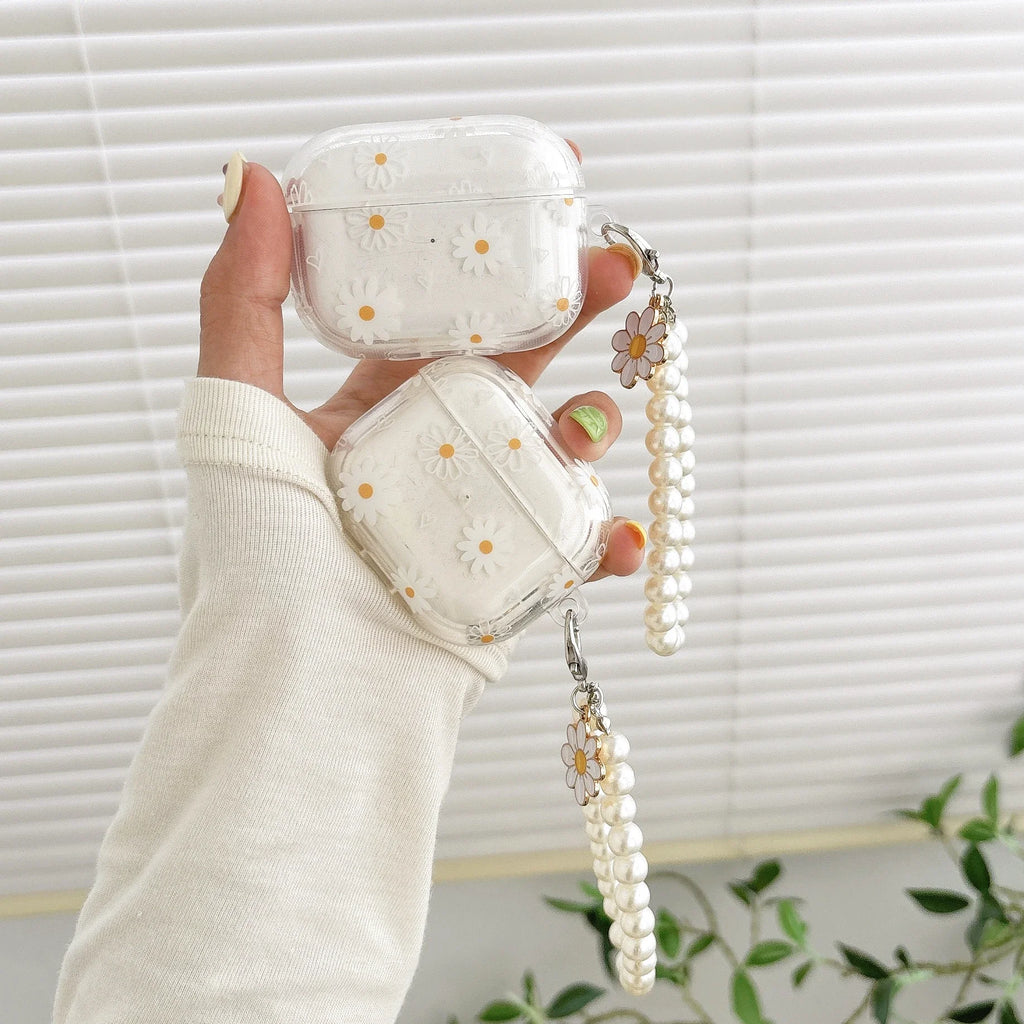 Clear AirPods case with white daisy pattern and pearl beaded charm strap. Compatible with standard AirPods models.