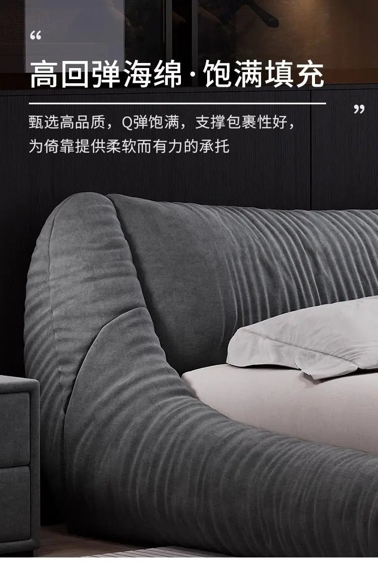 Close-up of a modern, charcoal grey upholstered bed frame with a textured, curved headboard for comfortable support.