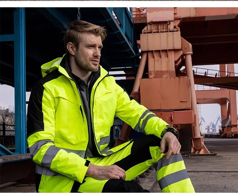A man wearing a neon yellow and black waterproof high-visibility jacket and trousers set with reflective safety strips.