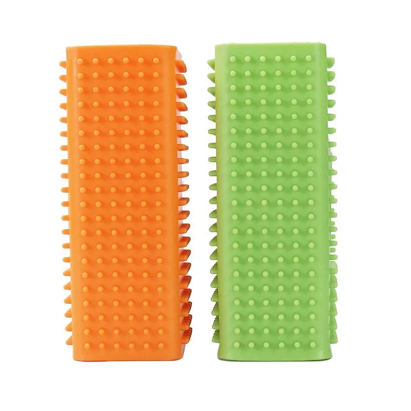 Two rectangular, rubberised pet dental chews in orange and green, featuring a textured, studded surface.