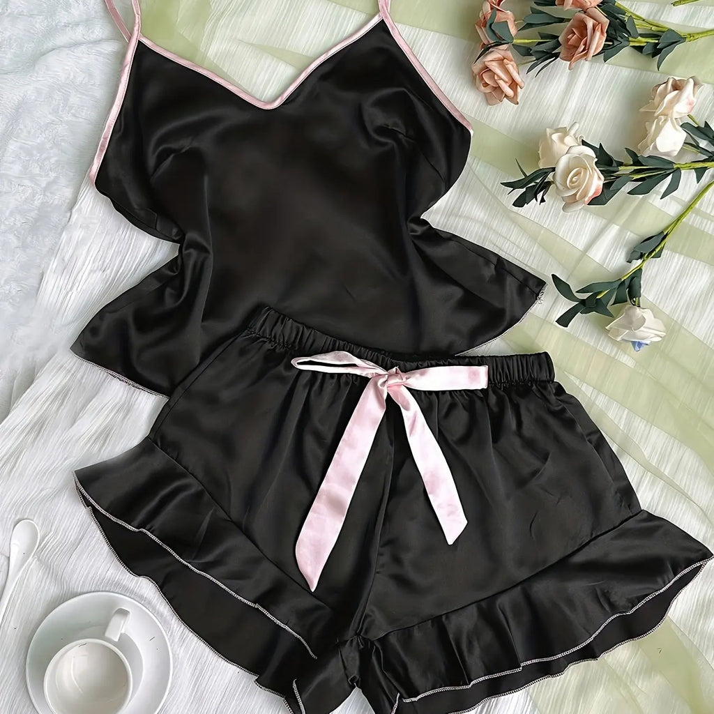 Black satin pyjama set with camisole and frilled shorts, featuring delicate pink trim and a decorative ribbon bow.