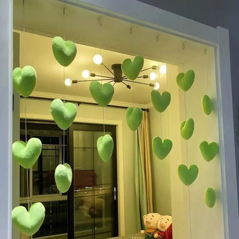 A hanging decorative curtain featuring plush, lime green hearts suspended on vertical strings against a doorway.