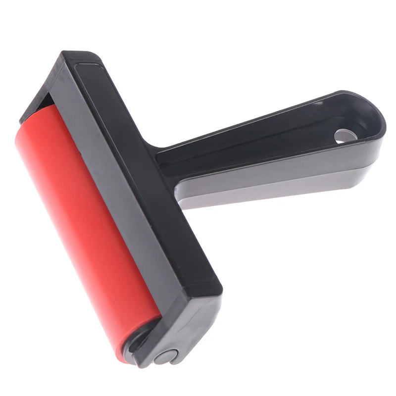Red rubber craft roller with a black plastic handle and integrated hanging hole, set against a white background.