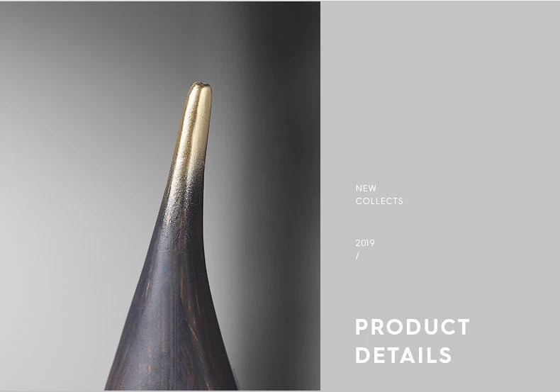 Close-up of a modern, abstract resin sailboat ornament with a textured dark wood-grain finish and a gold-tipped top.