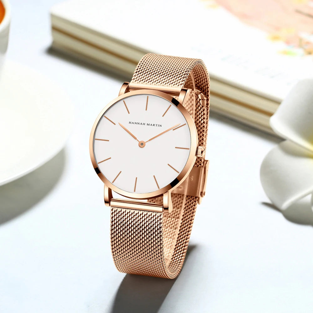 Rose gold women's watch with a round white dial, minimalist markers, and a mesh metal strap.