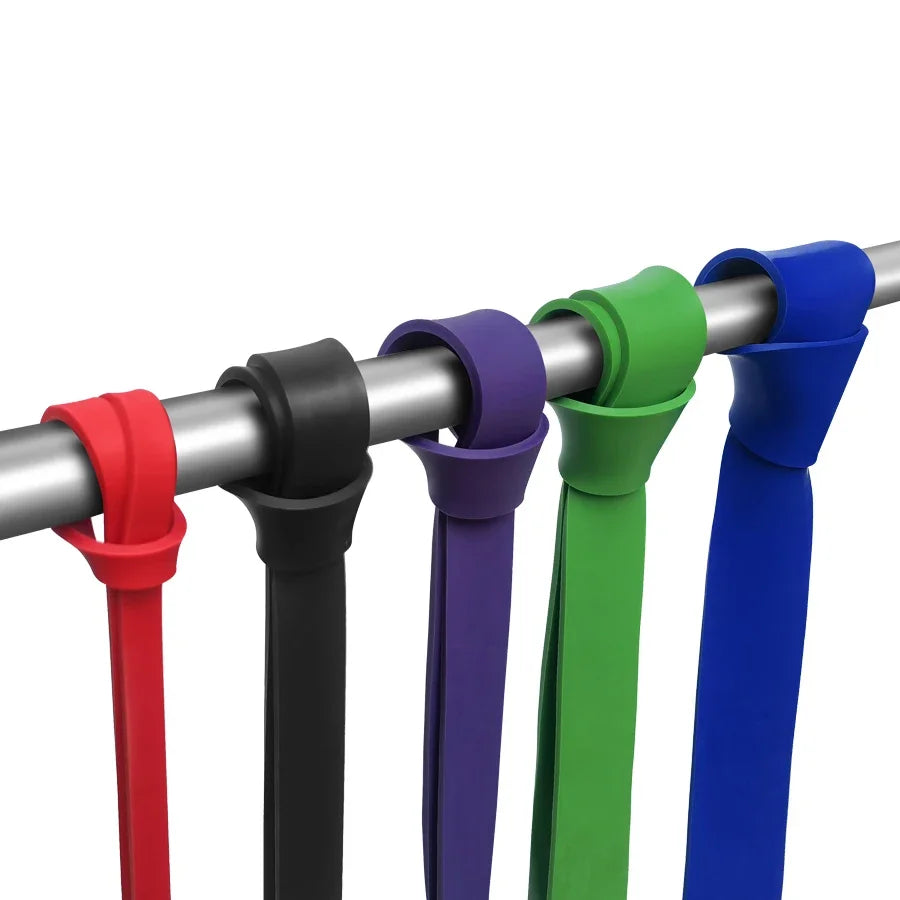 Five colourful resistance bands looped over a horizontal metal pole, in red, black, purple, green, and blue.