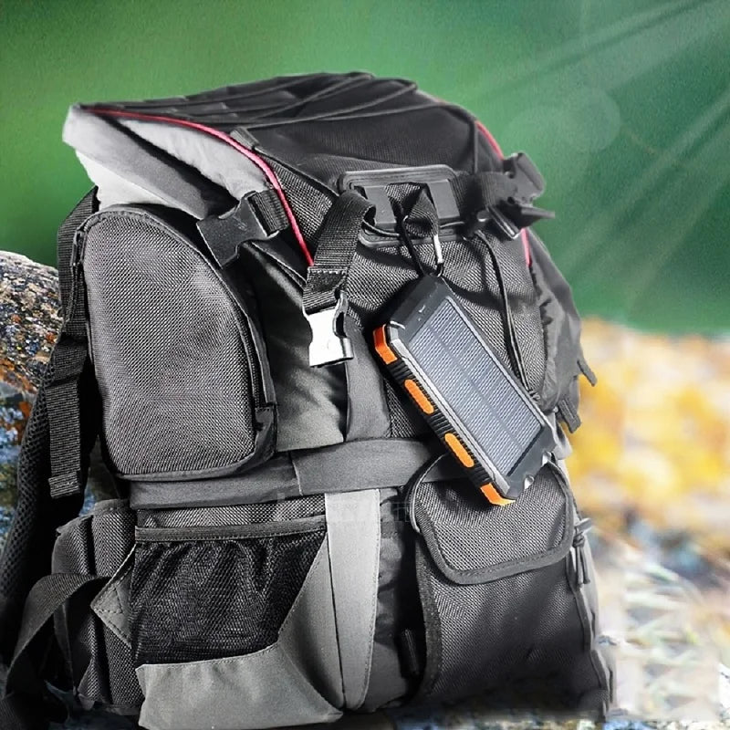 Black and orange rugged solar power bank hanging from a black outdoor rucksack.