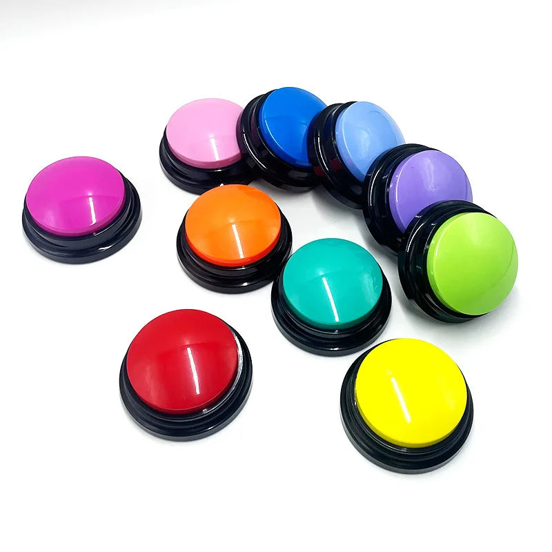 A collection of colourful, circular, recordable dog training buttons with black bases, arranged on a white background.