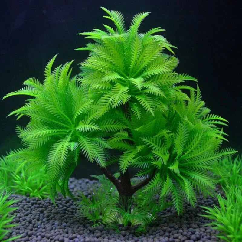 Artificial green aquarium plant with palm-like fern fronds on a dark brown trunk, set on dark gravel.