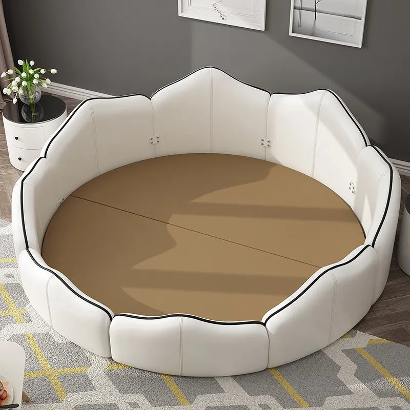 Luxury white round bed frame with a tan mattress and elegant black-piped upholstered petal-shaped headboard.