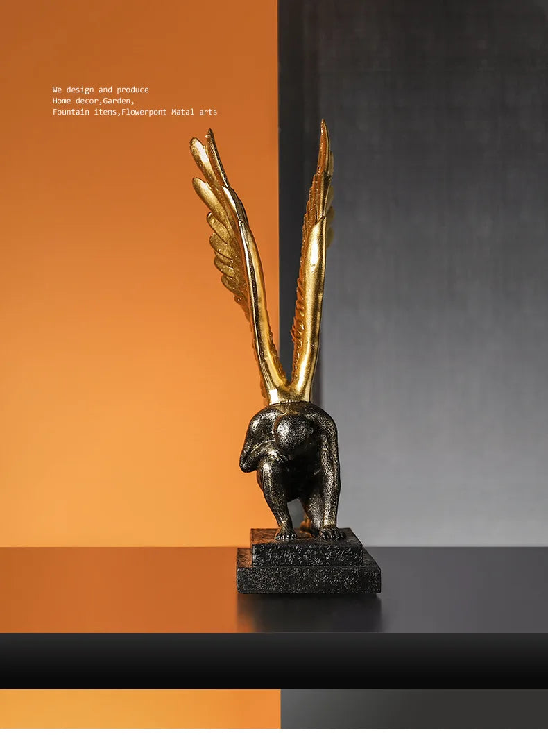 Decorative sculpture of a kneeling figure with large, metallic gold wings on a textured black base.