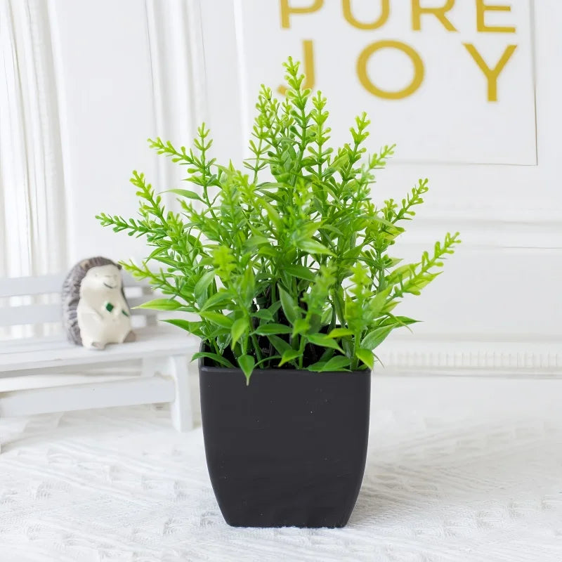 Artificial bright green plant in a matte black square pot, set against a white background with a small hedgehog figurine.