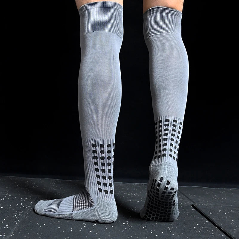 Grey over-the-calf sports socks with black grip patterns on the heels and soles for enhanced traction.