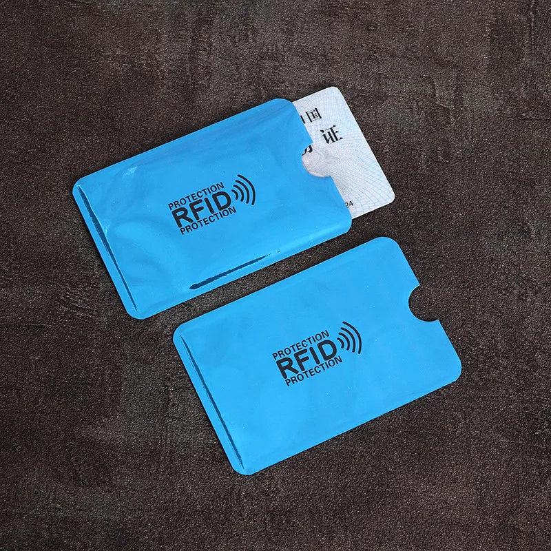 Two light blue RFID-blocking plastic sleeves for cards, one holding a card, on a dark textured background.