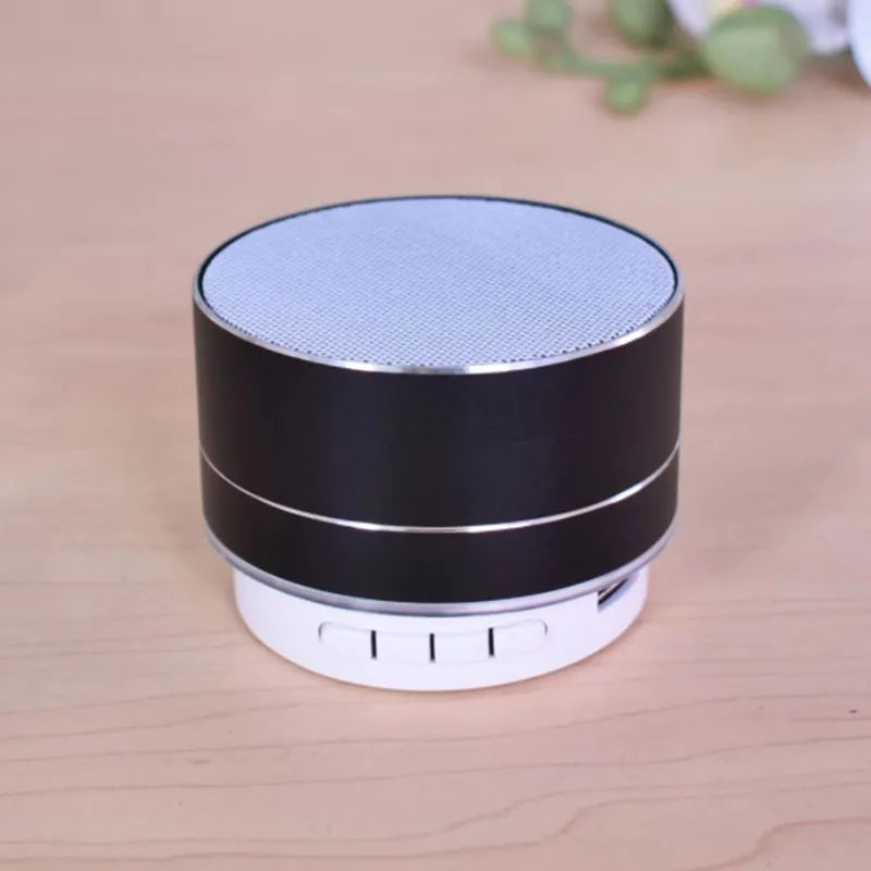 Portable black aluminium Bluetooth speaker with a metallic silver top and white base with control buttons.