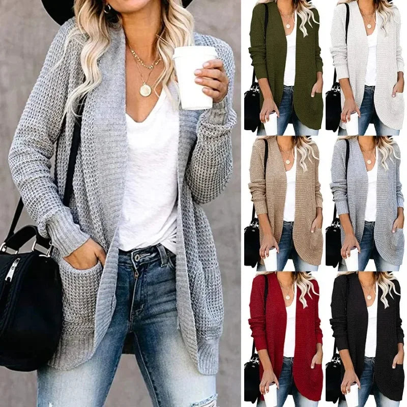 Grey open-front knitted cardigan sweater with long sleeves, ribbed trim, and front pockets, worn over a white top.