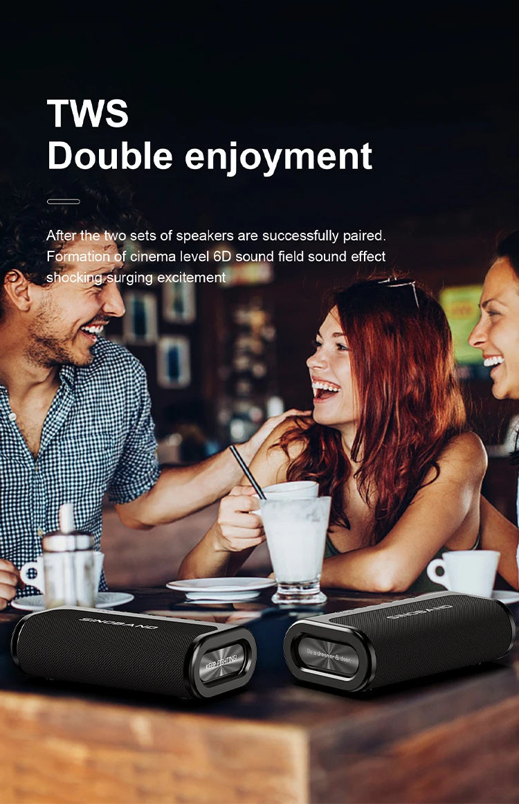 Two sleek, black 80W portable Bluetooth speakers paired together on a table in front of a smiling group of friends.