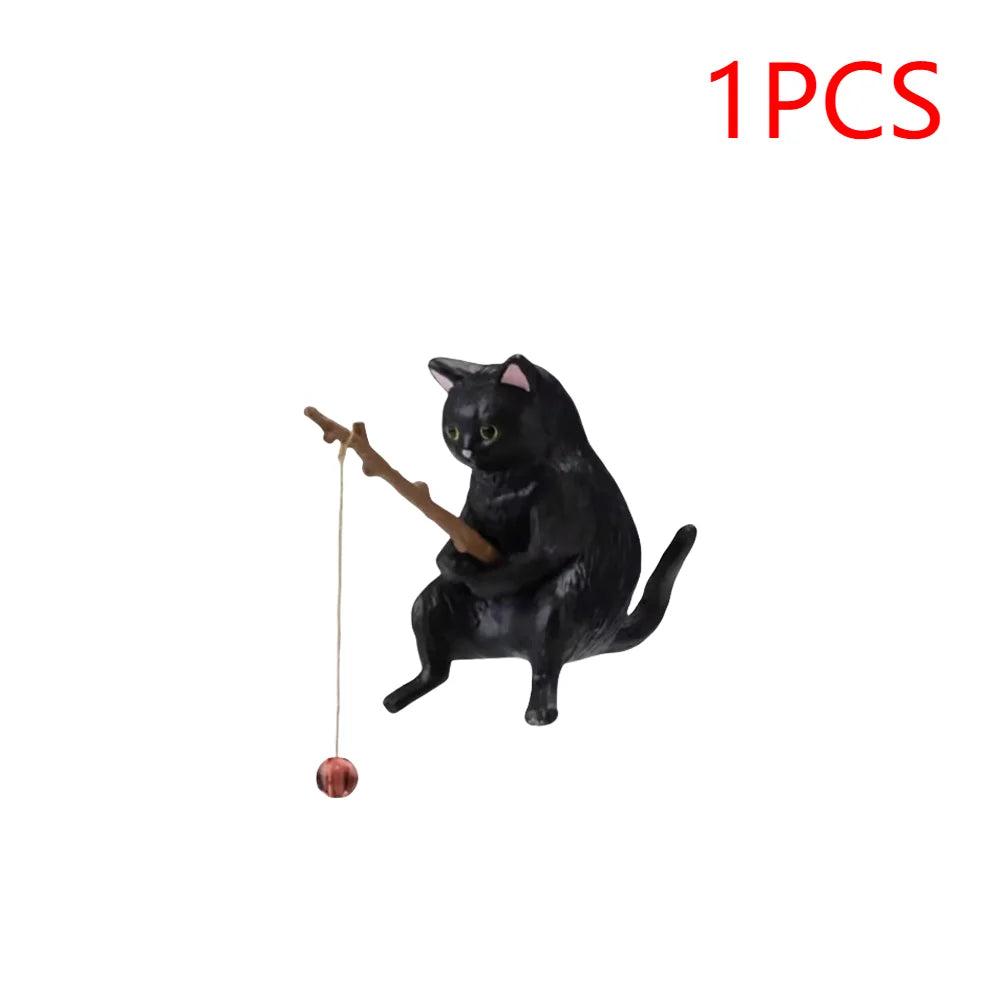 A small, black cat aquarium ornament holding a wooden fishing rod with a hanging red bauble.