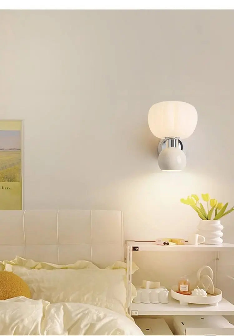 Modern cream-style wall lamp with a globe glass shade and a chrome accent in a cosy bedroom setting.