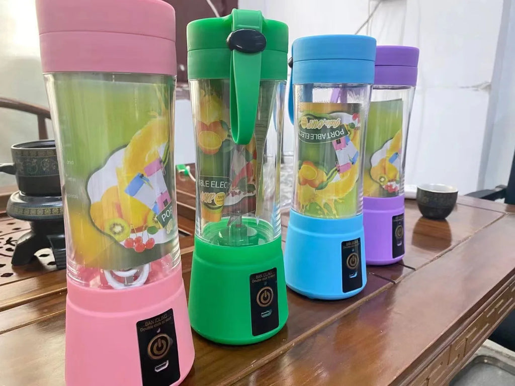 Four portable electric blenders in pink, green, blue, and purple, featuring clear bodies and bottom power buttons.