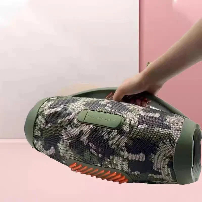 A hand holds a portable, camo-print 100W waterproof Bluetooth speaker with a sturdy handle and vibrant RGB accents.