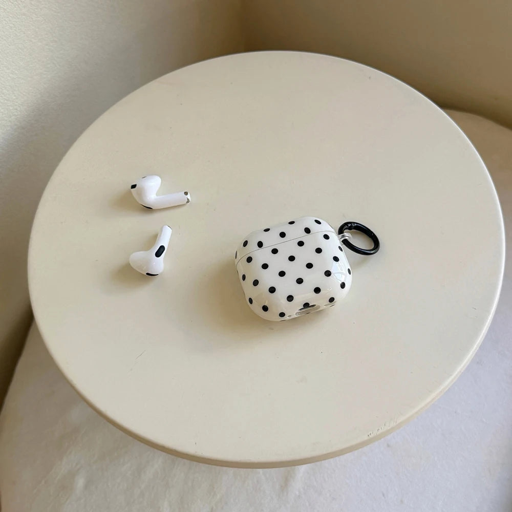 White AirPods case with black polka dots, glossy finish, and black carabiner, suitable for AirPods (1st/2nd Gen).