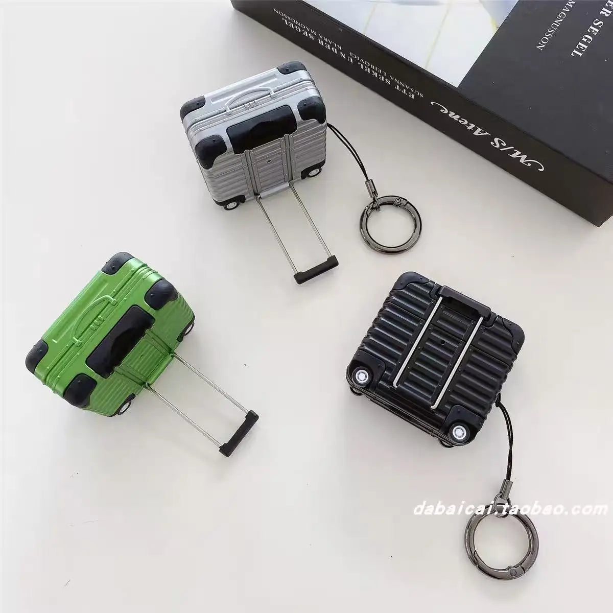 Suitcase-style AirPods cases in silver, green and black, with retractable handles and keyring attachment.