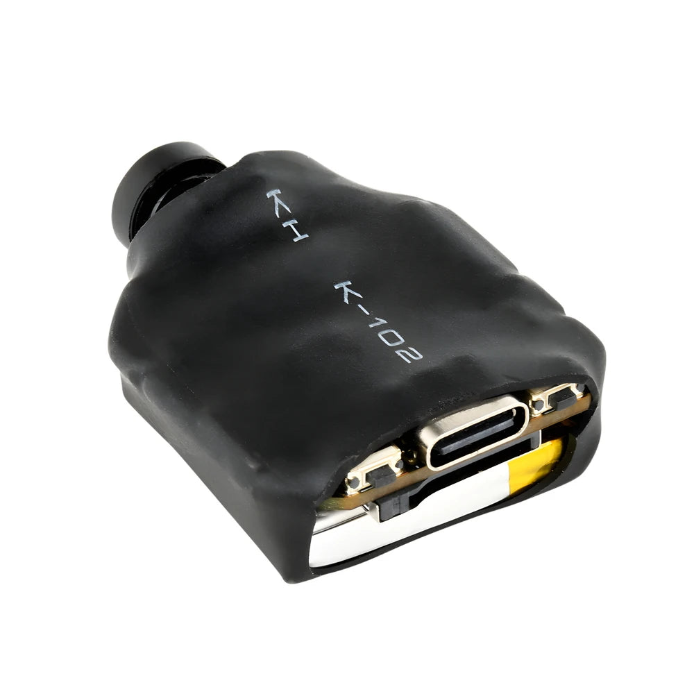 Black K-102 micro camera module with a plastic casing, lens, USB-C port, and internal battery on a white background.