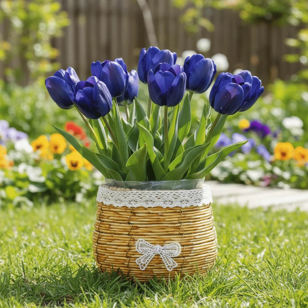 A rustic woven basket with lace trim and a white bow, holding a bouquet of vibrant deep blue tulips on green grass.