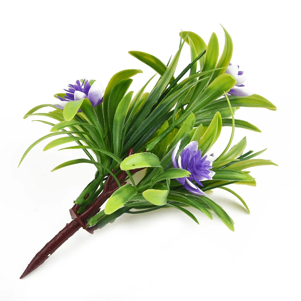Artificial bouquet of spiky green leaves and small purple-and-white flowers on a brown plastic stem.