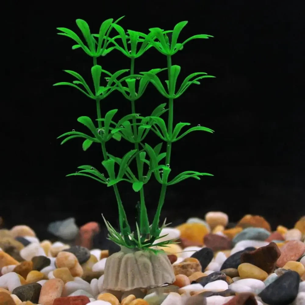 Artificial green aquarium plant with tiered leaves, set in a weighted base on a bed of multi-colored aquarium gravel.