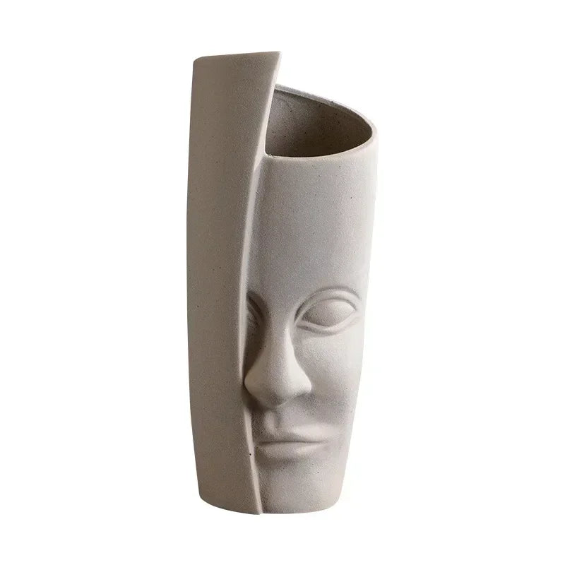 Matte beige ceramic vase with a contemporary abstract face design and a unique split, asymmetrical silhouette.