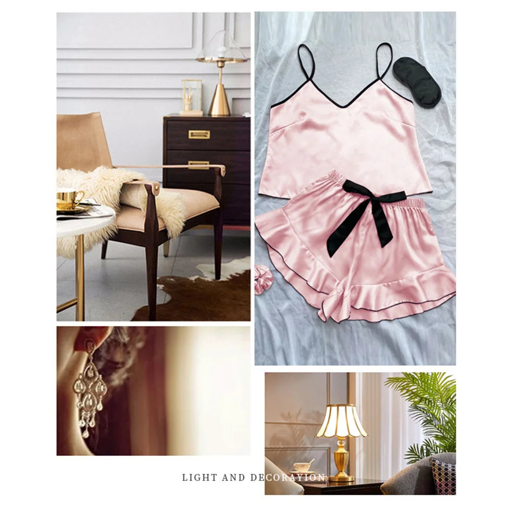 Pink satin pyjama set featuring a camisole top, frill-hem shorts with black bow, and a matching sleep mask.
