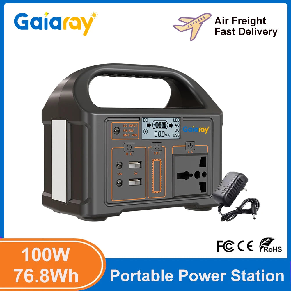 A dark gray portable power station with an AC outlet, DC ports, and USB ports, shown with its AC adapter.