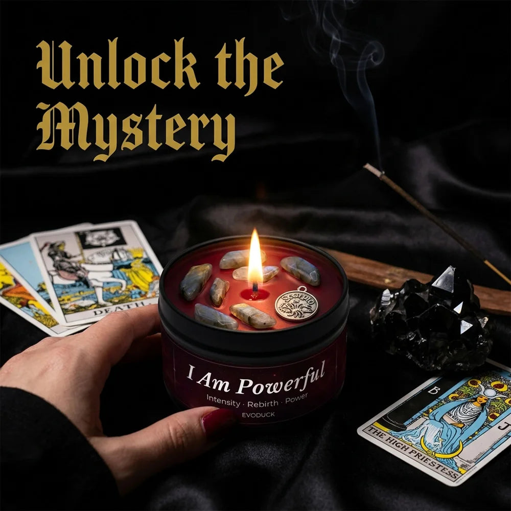 Red scented candle in a black tin, topped with crystals and a metal charm, surrounded by tarot cards on black silk.