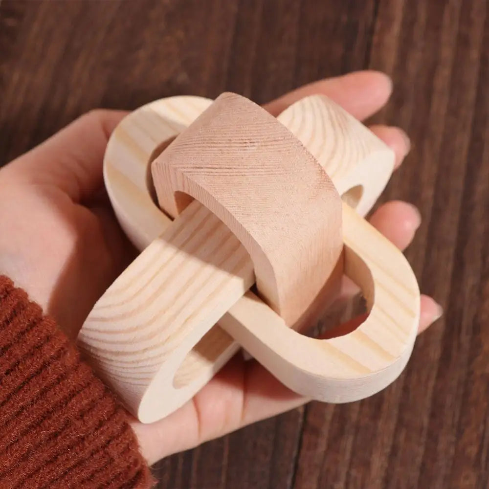 Interlocking natural wood puzzle toy with a smooth, rounded knot design, held in a hand.