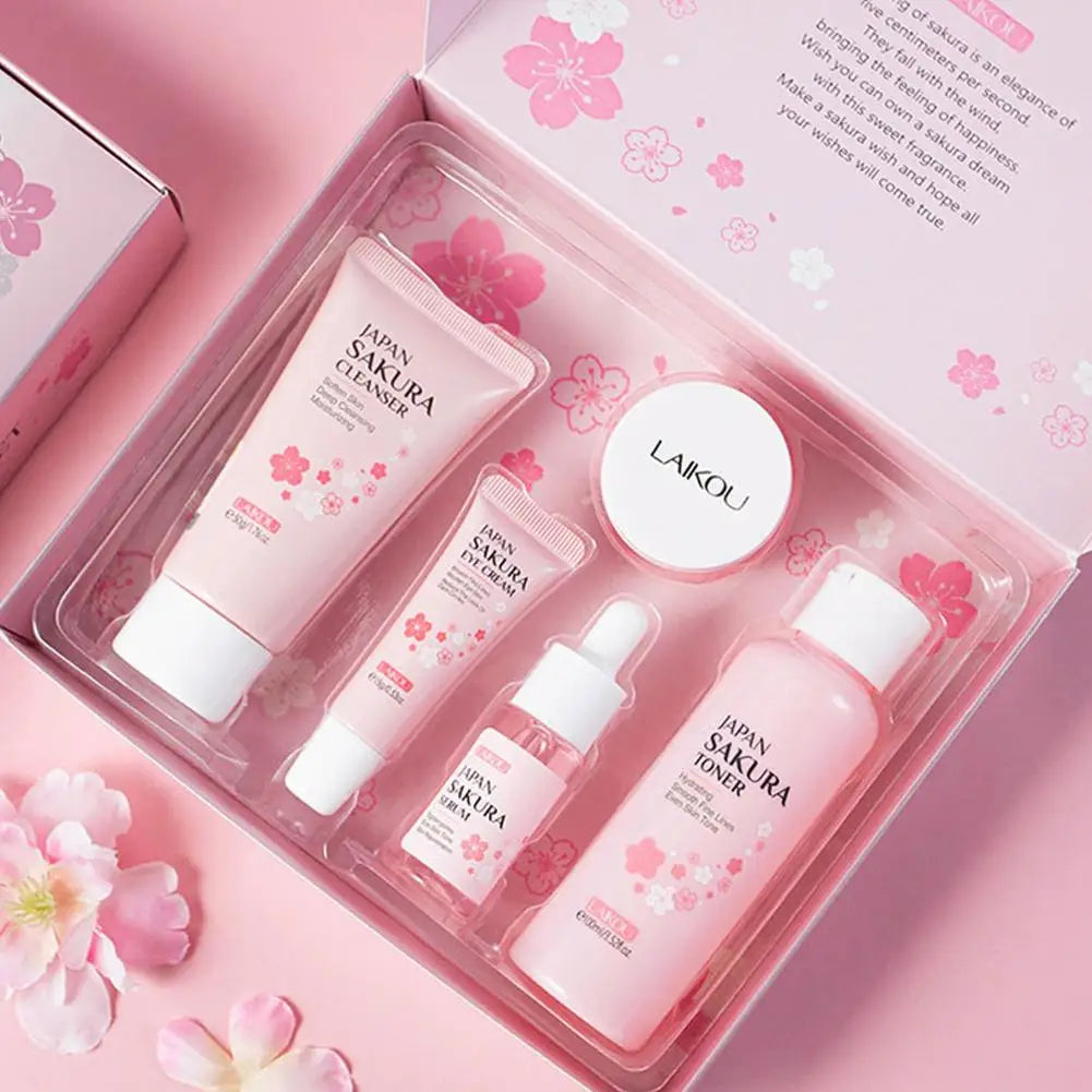 Pink skincare gift set including cleanser, eye cream, serum, face cream, and toner, packaged in a floral-themed box.