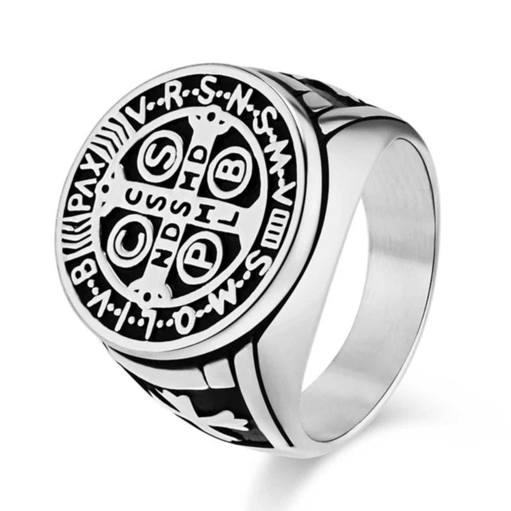 A silver-coloured stainless steel ring featuring an engraved circular Saint Benedict cross design.