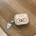 Clear Rilakkuma AirPods case with glasses graphic and matching acrylic charm on a wooden table.