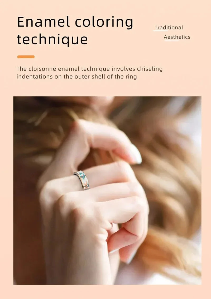 Elegant smart fitness ring with a white, floral cloisonné enamel finish worn on a finger.