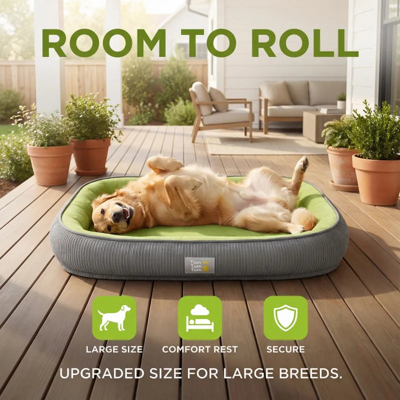 Rectangular green and grey dog bed on a wooden deck, featuring a raised bolster and a happy golden retriever lying on its back.