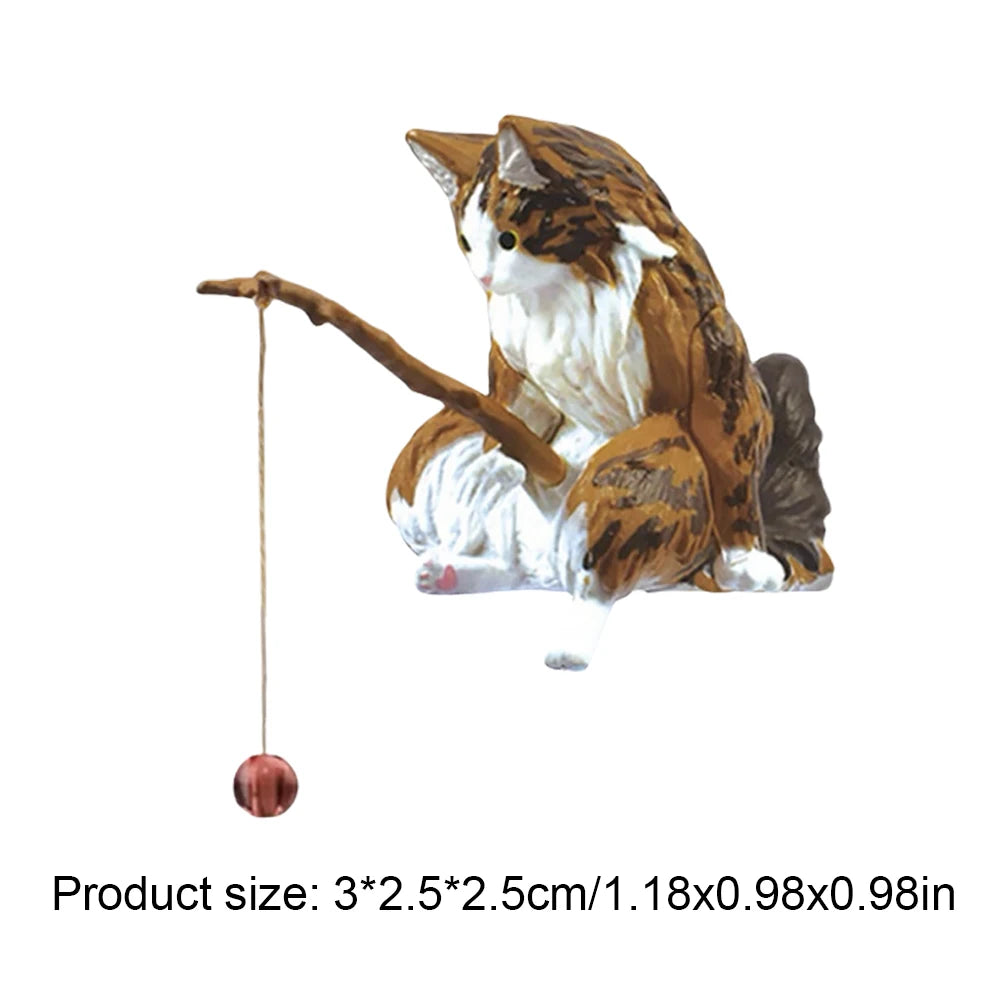 Small, painted resin ornament of a tortoiseshell cat holding a fishing rod with a tiny red ball on the line.