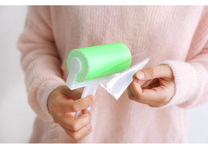 A person holding a lime green, reusable sticky lint roller with a white handle, peeling off a clear protective film.