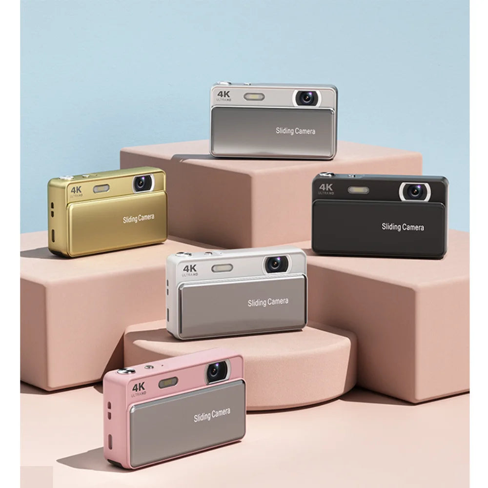 Five compact 4K digital cameras with sliding lens covers in gold, silver, black, white, and pink metallic finishes.
