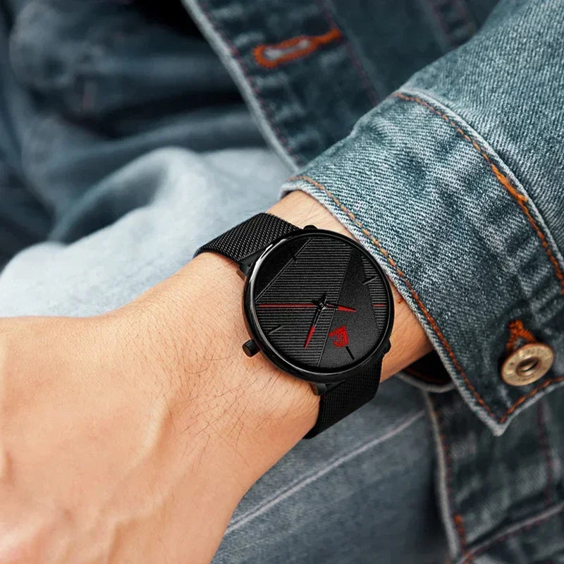 Minimalist men’s ultra-thin watch with a black mesh strap, textured black dial, and striking red hands.