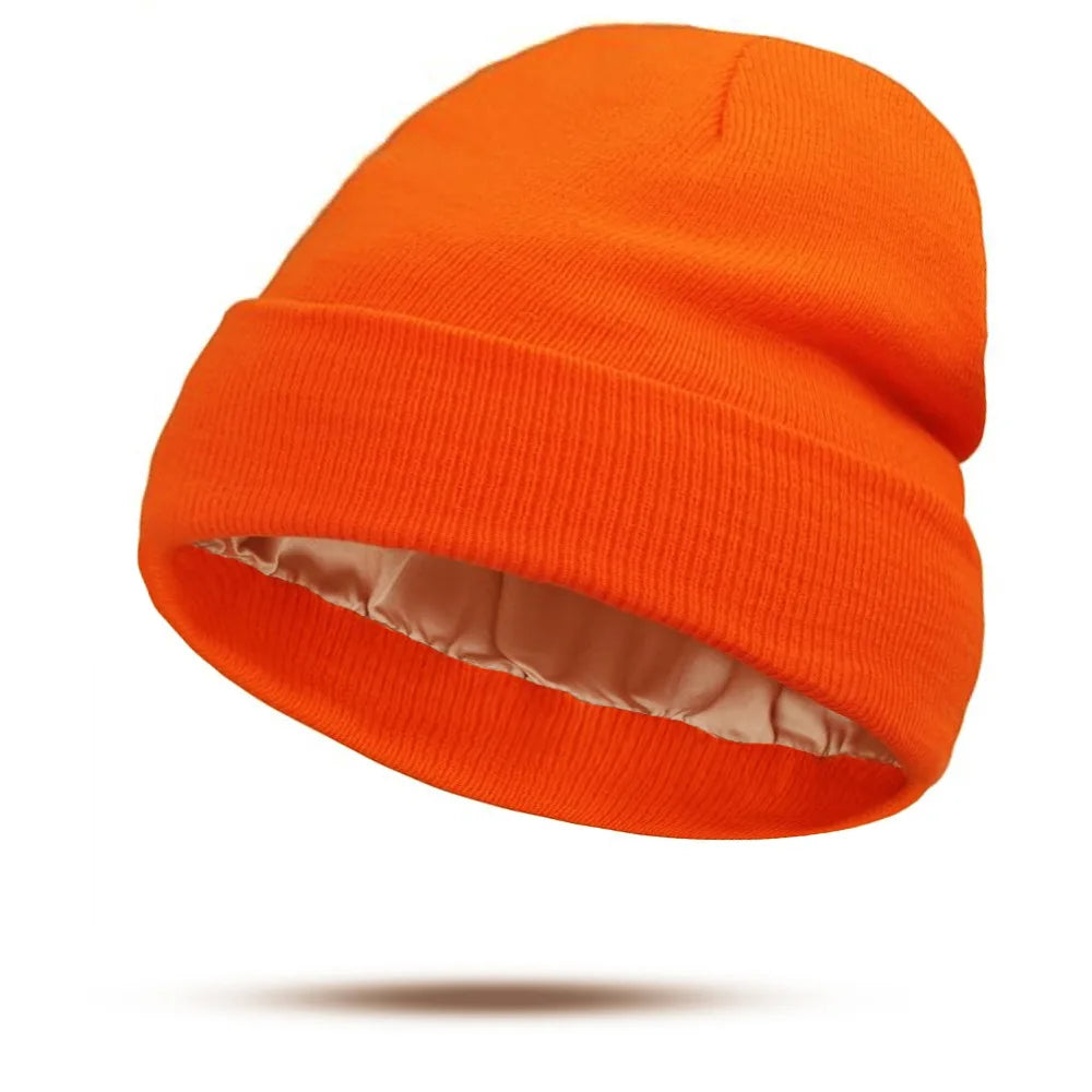 Bright orange knitted beanie hat with a smooth, cream-coloured satin lining.