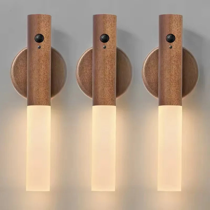 Three modern, bronze-finish rechargeable LED wall lights with motion sensors and soft glowing vertical frosted panels.