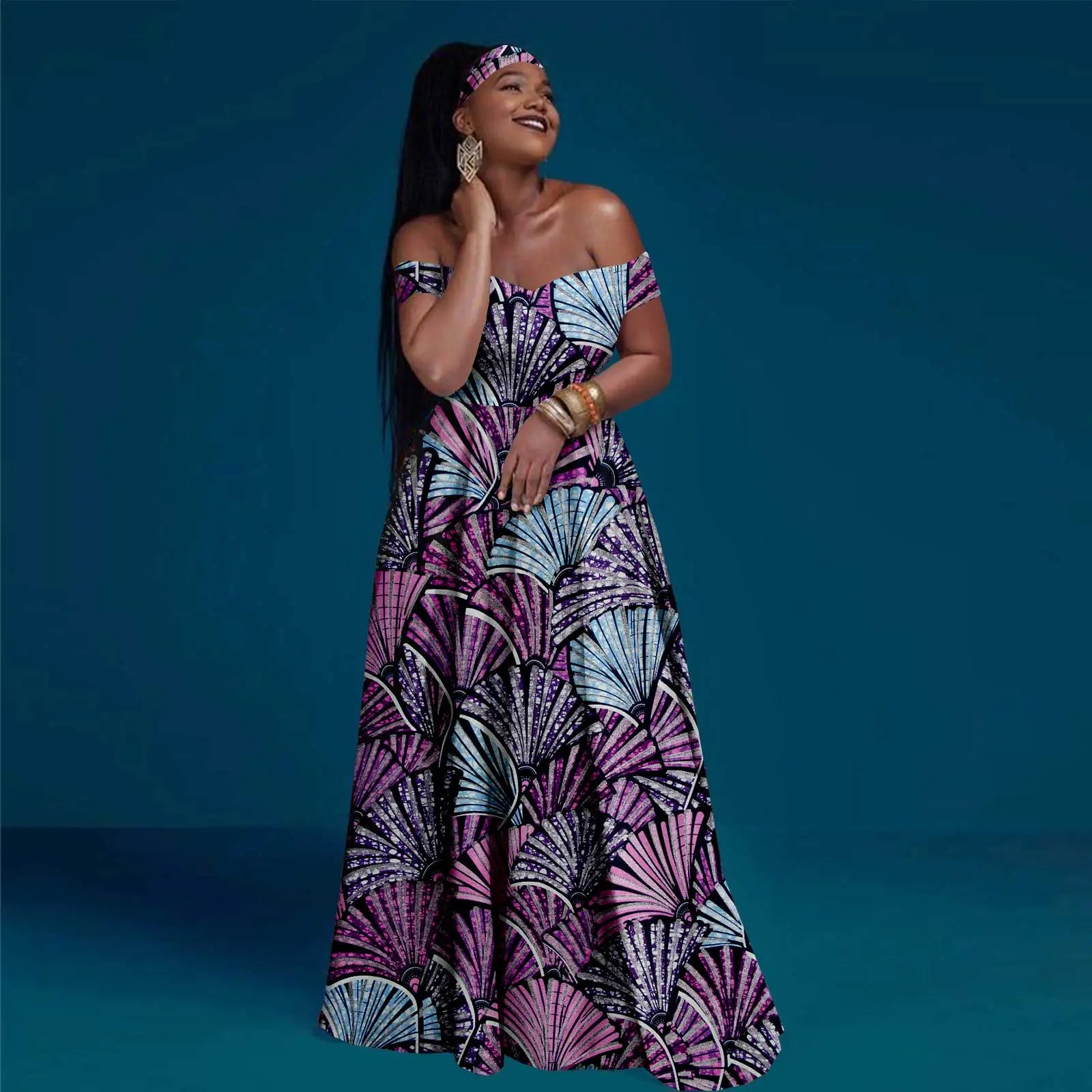 A woman models an off-the-shoulder maxi dress in purple and blue with a geometric fan-shaped print.
