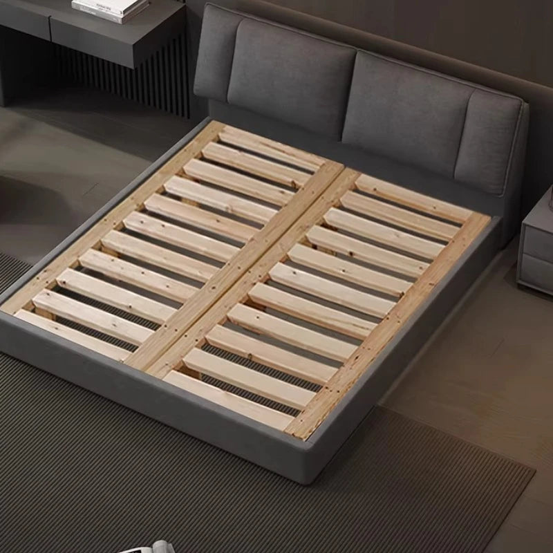 Modern charcoal grey upholstered double bed frame with a panelled headboard and exposed wooden slats.