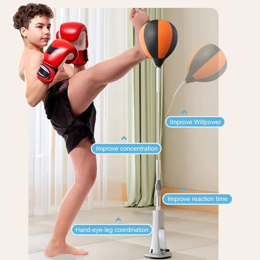 Height-adjustable black and orange speed bag with a silver stand, spring base, and a child kicking the bag.